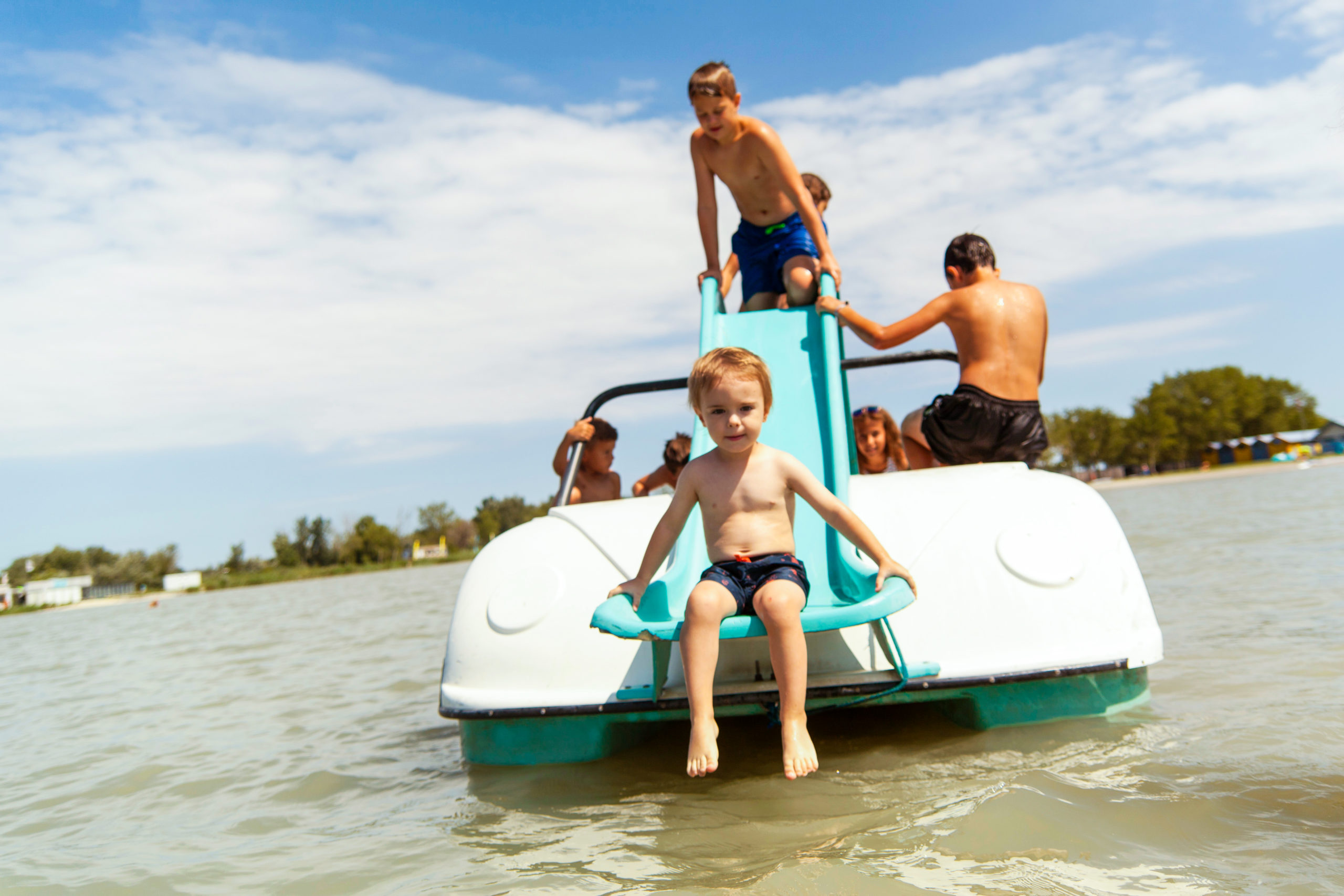Kinder fahren mit dem Tretboot auf dem Neusiedlersee und sitzen auf der Rutsche